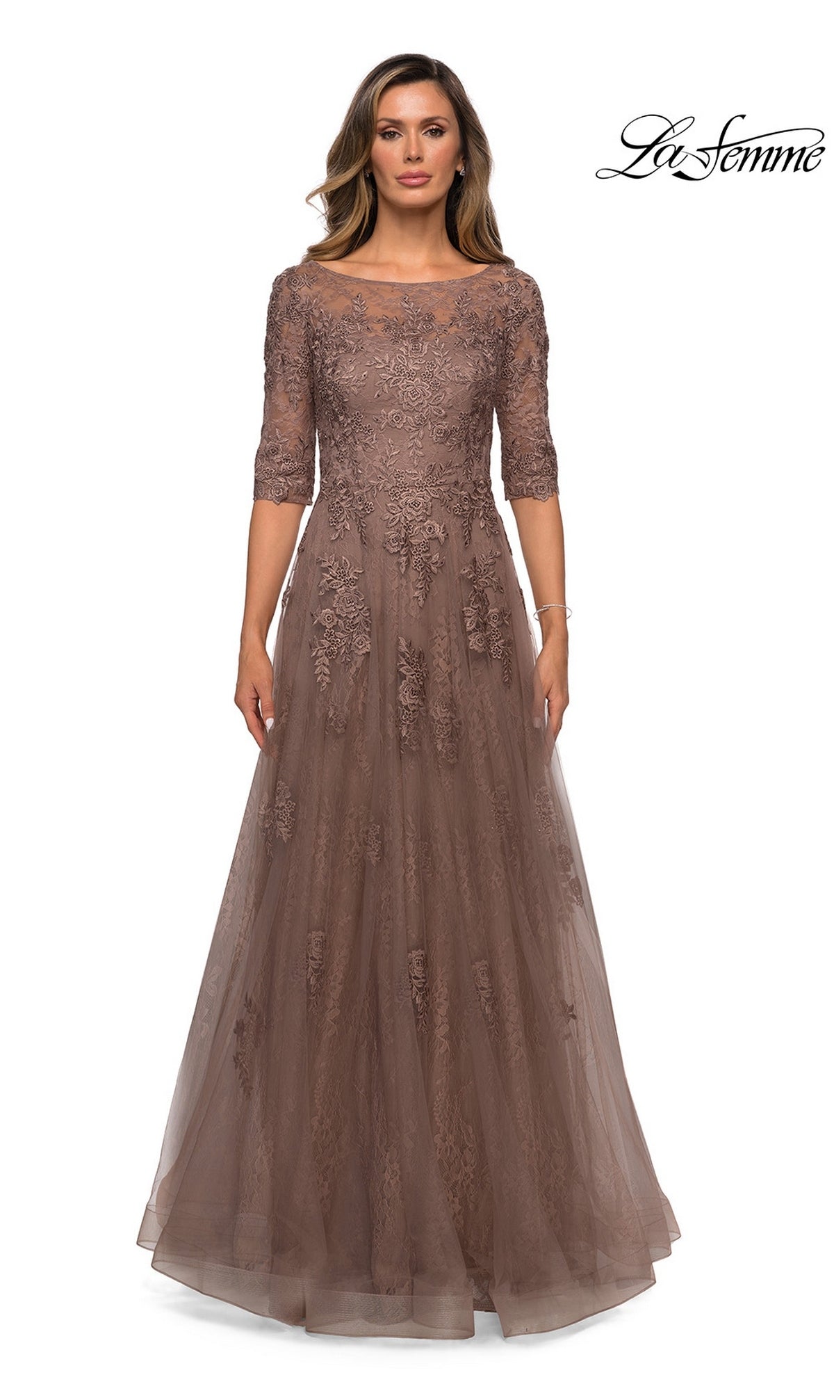 A woman wears the Long Formal Dress: La Femme 28036, a mauve lace gown with half sleeves and floral embroidery, against a white background.